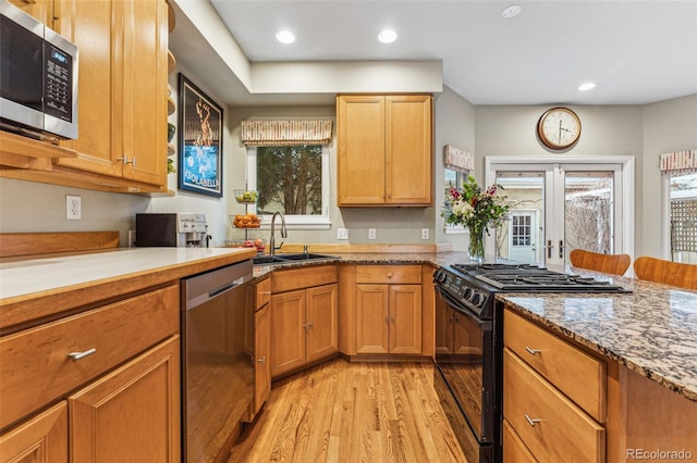 kitchen featuring light wood finished floors, light stone countertops, recessed lighting, appliances with stainless steel finishes, and a sink