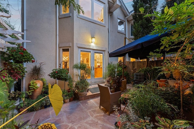 rear view of house with french doors, fence, a patio area, and stucco siding