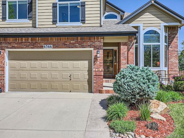 6366 Umber Cir, Arvada, CO 80403 - doorway to property with brick siding, a shingled roof, an attached garage, and concrete driveway