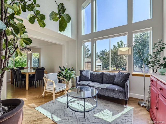 6366 Umber Cir, Arvada, CO 80403 - living room featuring a towering ceiling, light wood-type flooring, baseboards, and a chandelier