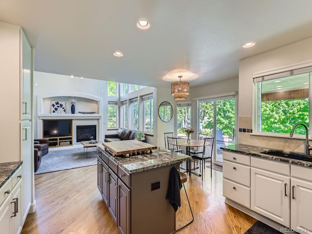 6366 Umber Cir, Arvada, CO 80403 - kitchen featuring a sink, dark stone countertops, white cabinets, light wood finished floors, and recessed lighting