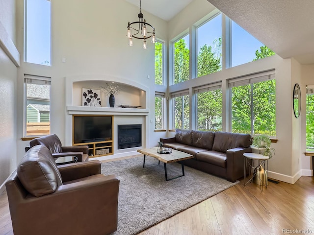 6366 Umber Cir, Arvada, CO 80403 - living area featuring a towering ceiling, healthy amount of natural light, hardwood / wood-style floors, baseboards, and a chandelier