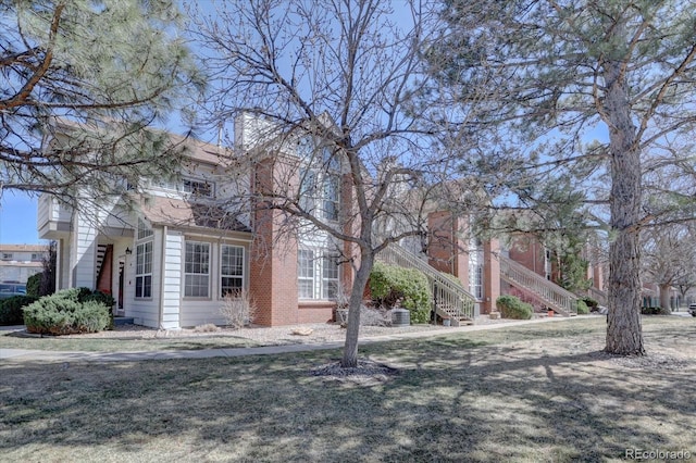 obstructed view of property with a front lawn and stairway