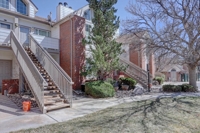 exterior space with brick siding, stairway, and a chimney