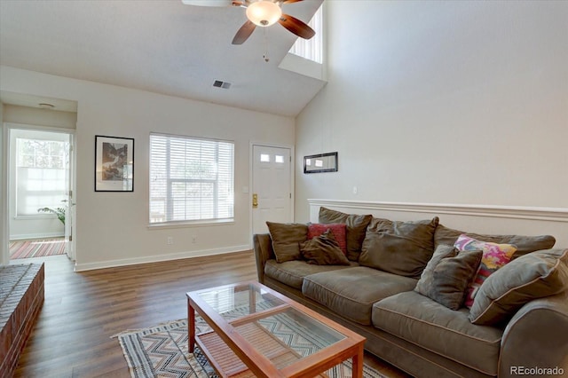 living room with a wealth of natural light, visible vents, wood finished floors, and a ceiling fan