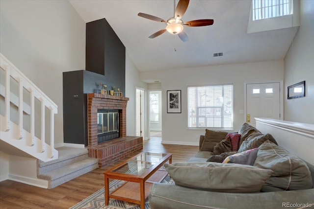 living area featuring a ceiling fan, wood finished floors, high vaulted ceiling, and visible vents