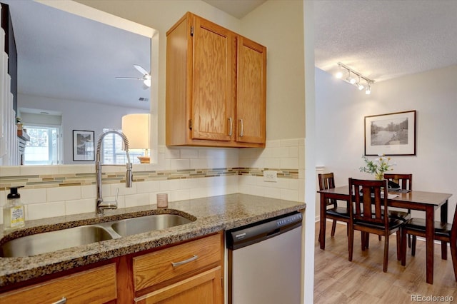 kitchen with a sink, light stone countertops, dishwasher, a textured ceiling, and ceiling fan
