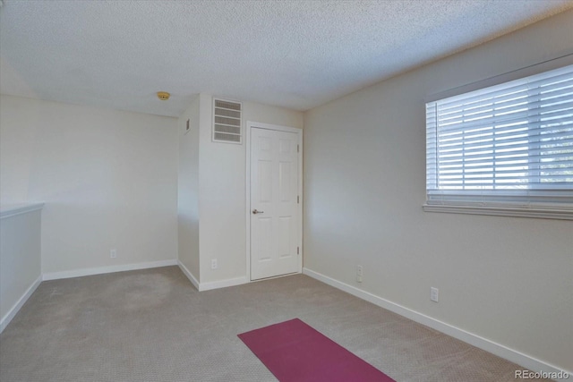 empty room featuring baseboards, visible vents, carpet floors, and a textured ceiling