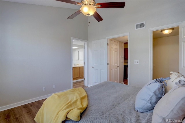 bedroom with a ceiling fan, wood finished floors, ensuite bath, baseboards, and visible vents