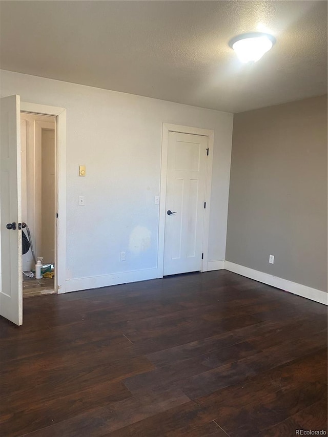 spare room featuring dark hardwood / wood-style flooring and a textured ceiling