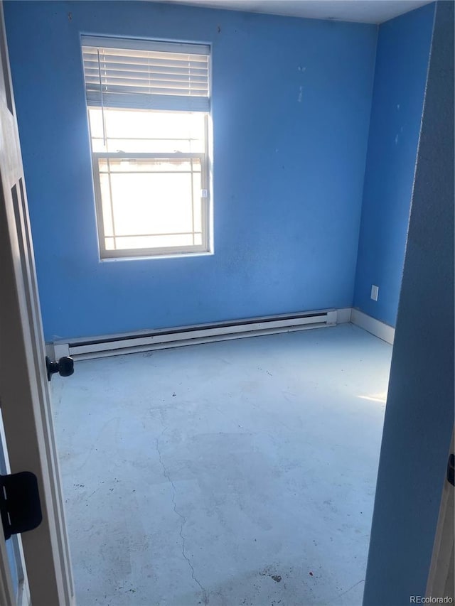 empty room featuring concrete floors and a baseboard heating unit