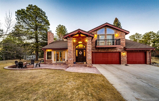 view of front of property with a balcony, driveway, a front lawn, and brick siding