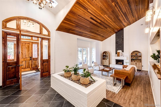 entryway with high vaulted ceiling, dark tile patterned floors, a fireplace, and wood ceiling