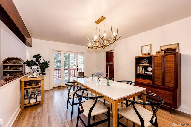 dining space featuring an inviting chandelier, baseboards, and light wood-style floors