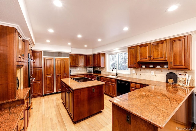 kitchen featuring light wood finished floors, backsplash, a kitchen island, light stone countertops, and black appliances