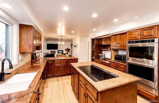 kitchen with recessed lighting, a sink, appliances with stainless steel finishes, a center island, and light wood finished floors