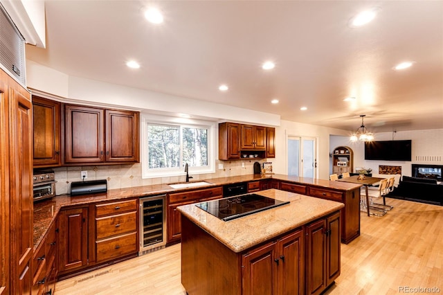 kitchen with black electric cooktop, beverage cooler, a sink, light wood-type flooring, and tasteful backsplash