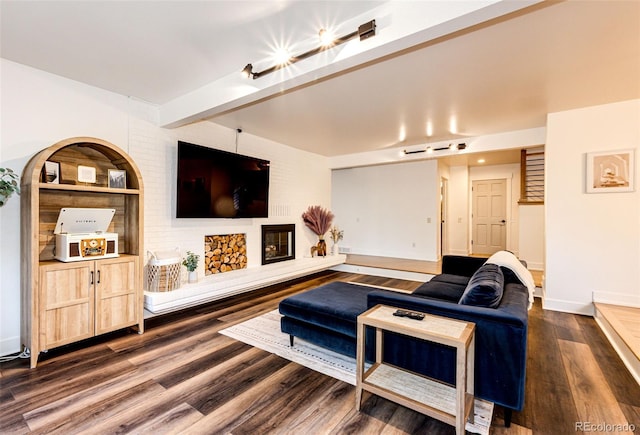 living room featuring a fireplace, baseboards, dark wood-style flooring, and beamed ceiling