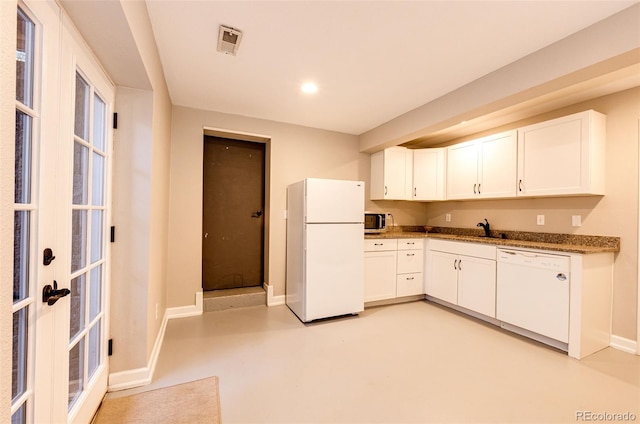 kitchen with white cabinetry, a sink, white appliances, concrete floors, and baseboards