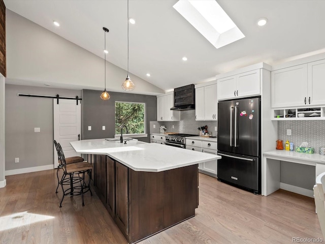 280 E 11th Ave, Broomfield, CO 80020 - kitchen featuring high end appliances, custom range hood, a barn door, a skylight, and tasteful backsplash