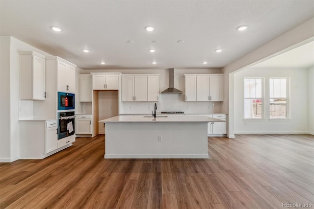 25284 E Warren Pl, Aurora, CO 80018 - kitchen with wall chimney range hood, stainless steel oven, light countertops, light wood-style flooring, and recessed lighting