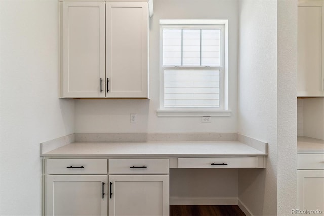25284 E Warren Pl, Aurora, CO 80018 - kitchen with built in study area, white cabinets, light countertops, and dark wood-type flooring