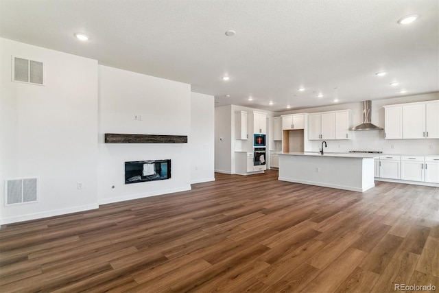 25284 E Warren Pl, Aurora, CO 80018 - unfurnished living room with wood finished floors, a glass covered fireplace, and recessed lighting