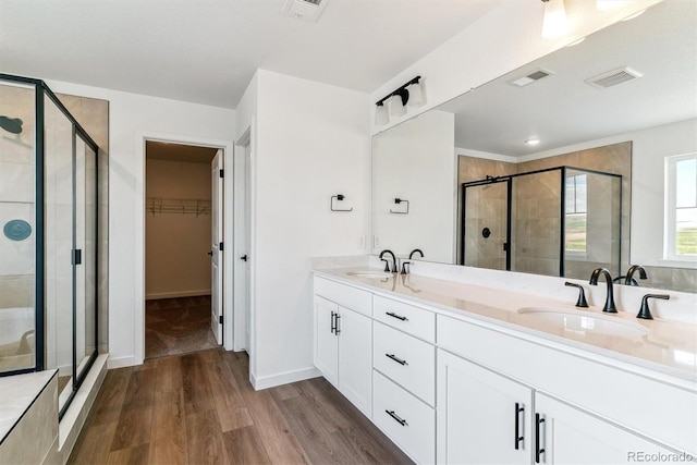 25284 E Warren Pl, Aurora, CO 80018 - full bathroom featuring a shower stall, wood finished floors, double vanity, and a walk in closet
