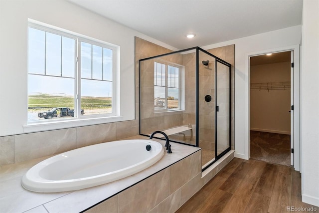 25284 E Warren Pl, Aurora, CO 80018 - bathroom featuring wood finished floors, a bath, a shower stall, a spacious closet, and recessed lighting