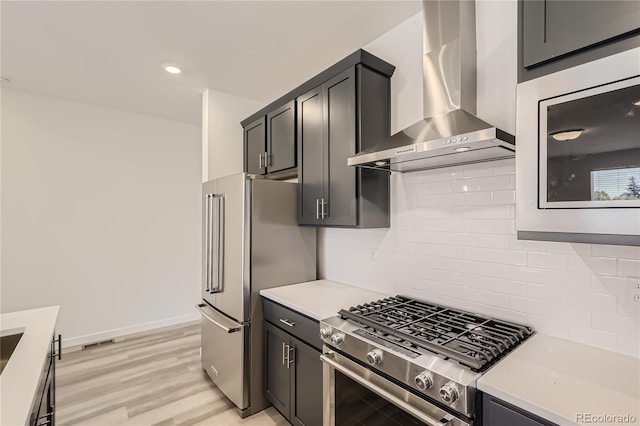 kitchen with light hardwood / wood-style floors, stainless steel appliances, tasteful backsplash, and wall chimney exhaust hood