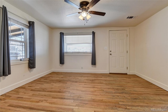 unfurnished room with visible vents, baseboards, ceiling fan, light wood-style floors, and a textured ceiling