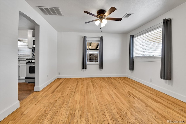 spare room featuring visible vents, baseboards, light wood-type flooring, and a ceiling fan