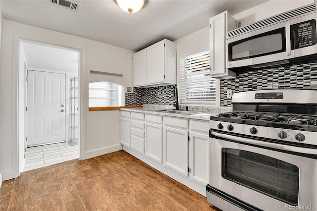 kitchen with visible vents, a sink, white cabinetry, stainless steel appliances, and light countertops