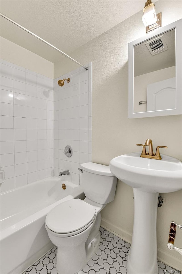 bathroom with baseboards, visible vents,  shower combination, a textured ceiling, and toilet