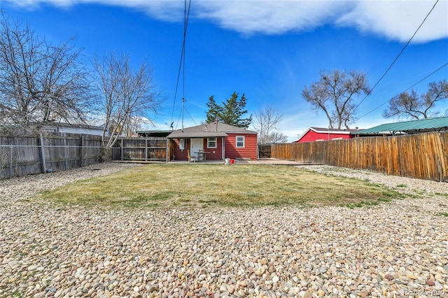 back of house with a lawn and a fenced backyard