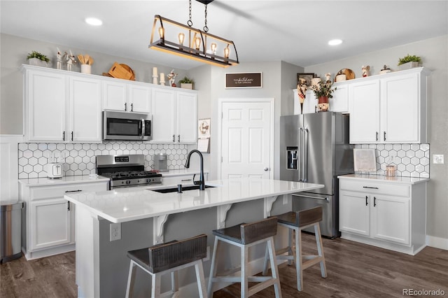 kitchen with stainless steel appliances, a kitchen island with sink, and white cabinets