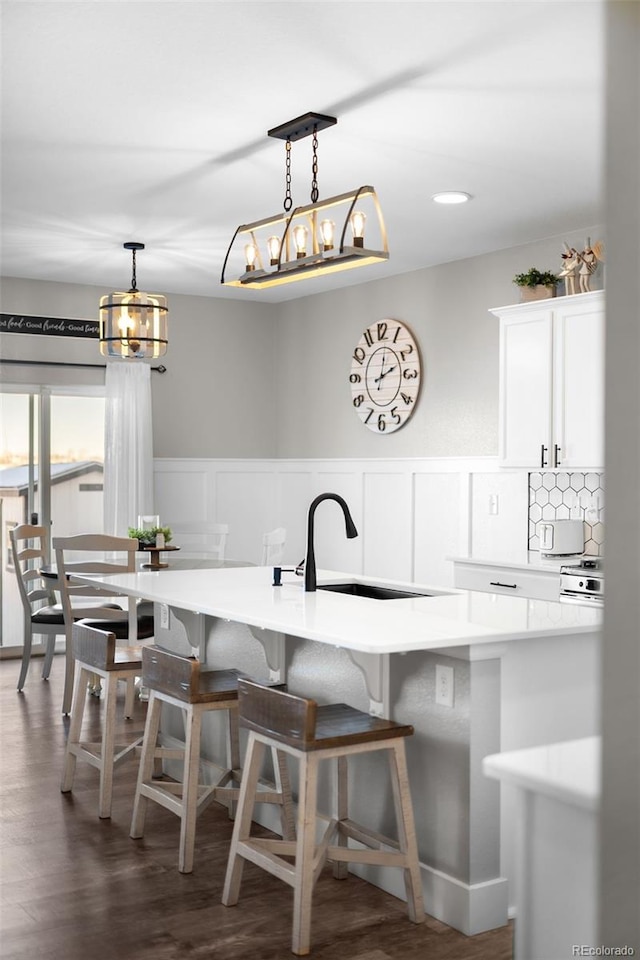 kitchen with hanging light fixtures, a breakfast bar area, sink, and white cabinets