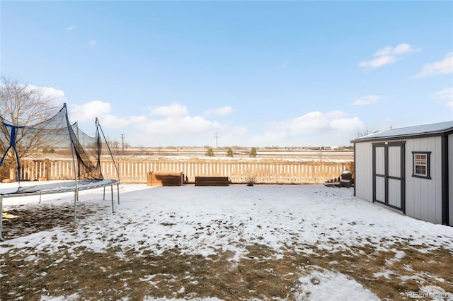 yard layered in snow with a trampoline and a storage shed