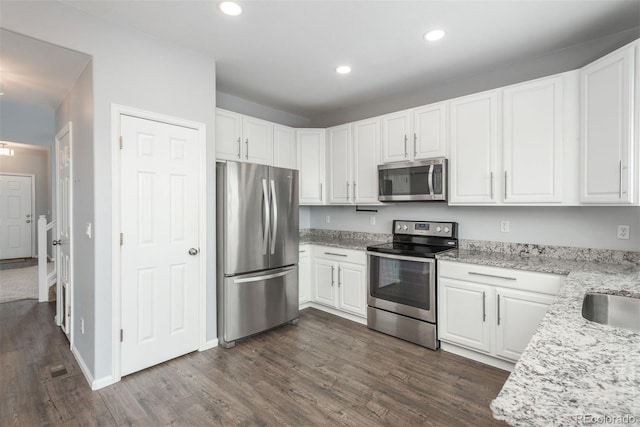 kitchen with light stone counters, stainless steel appliances, dark hardwood / wood-style floors, and white cabinets