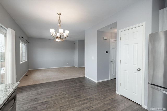 unfurnished dining area featuring an inviting chandelier and dark wood-type flooring