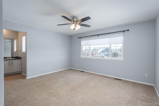 carpeted spare room featuring sink and ceiling fan