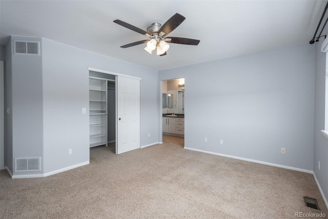 unfurnished bedroom with ceiling fan, connected bathroom, a closet, and light carpet