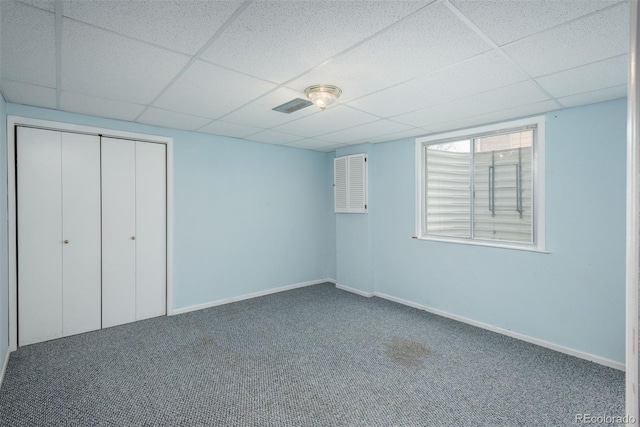 unfurnished bedroom with carpet flooring, a paneled ceiling, and a closet