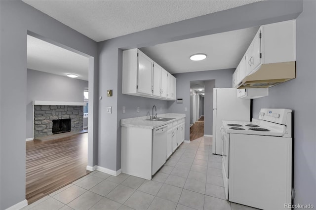 kitchen featuring white appliances, a sink, light countertops, under cabinet range hood, and light tile patterned floors