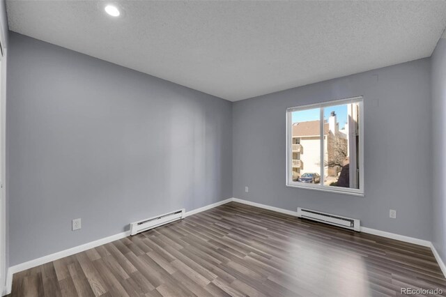 unfurnished room featuring baseboard heating, wood finished floors, baseboards, recessed lighting, and a textured ceiling