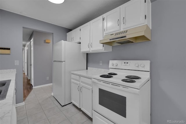 kitchen with under cabinet range hood, white appliances, white cabinets, light tile patterned flooring, and baseboards
