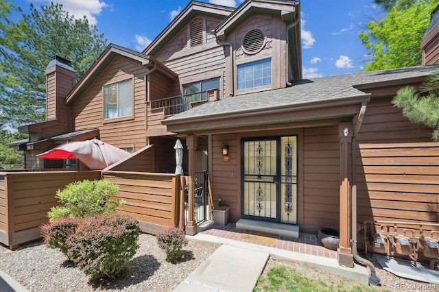 view of front of property featuring a balcony, a gate, fence, and a chimney