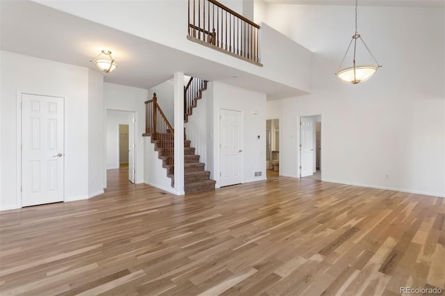 unfurnished living room featuring hardwood / wood-style flooring and a towering ceiling