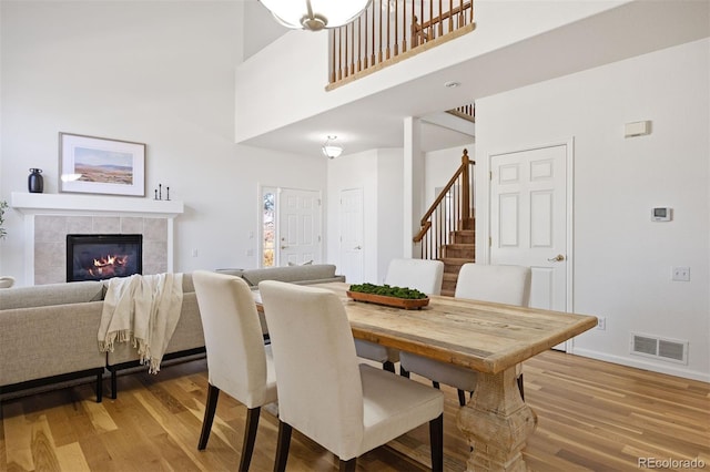 dining space with light wood-type flooring, visible vents, a fireplace, and stairs