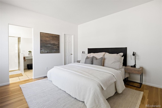 bedroom featuring ensuite bath, light wood-style flooring, and baseboards